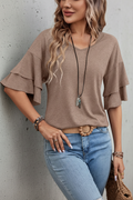 S35 taupe ruffle sleeve top with grey concrete background